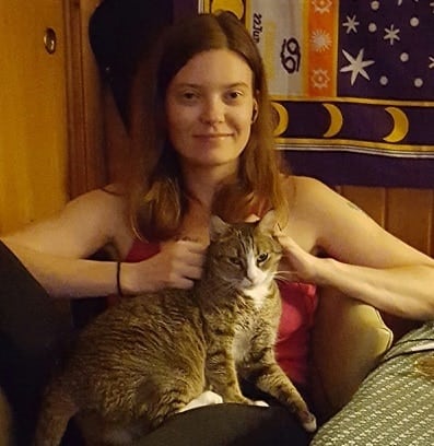 Kvinde i lyserød skjorte sidder med en kat på skødet